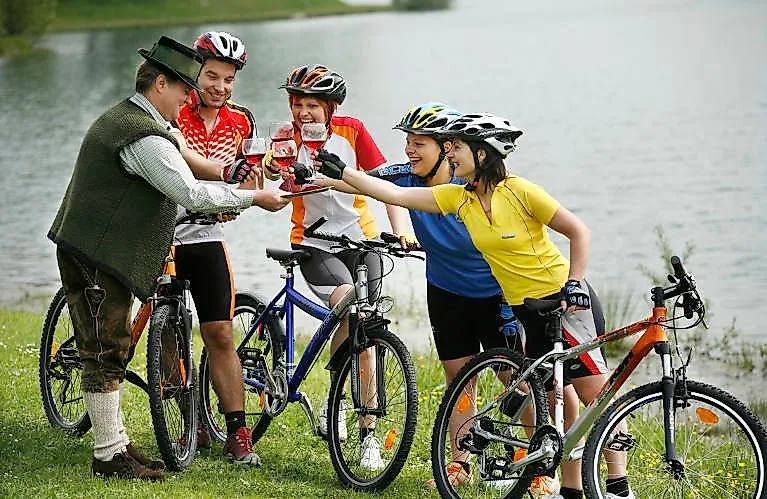 Gruppo di ciclisti brinda con uno stiriano durante un tour in bicicletta presso un lago a Bad Radkersburg.