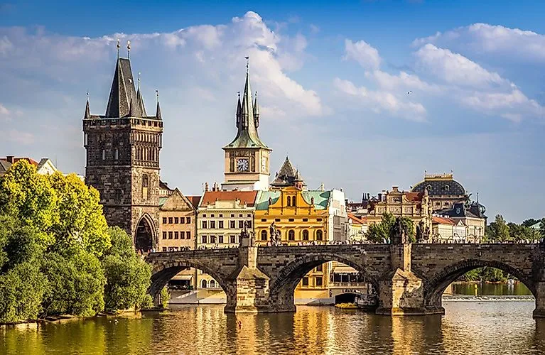 Zomers uitzicht op de Karelsbrug in Praag met historische brugtoren en oude stadshuizen onder een blauwe hemel