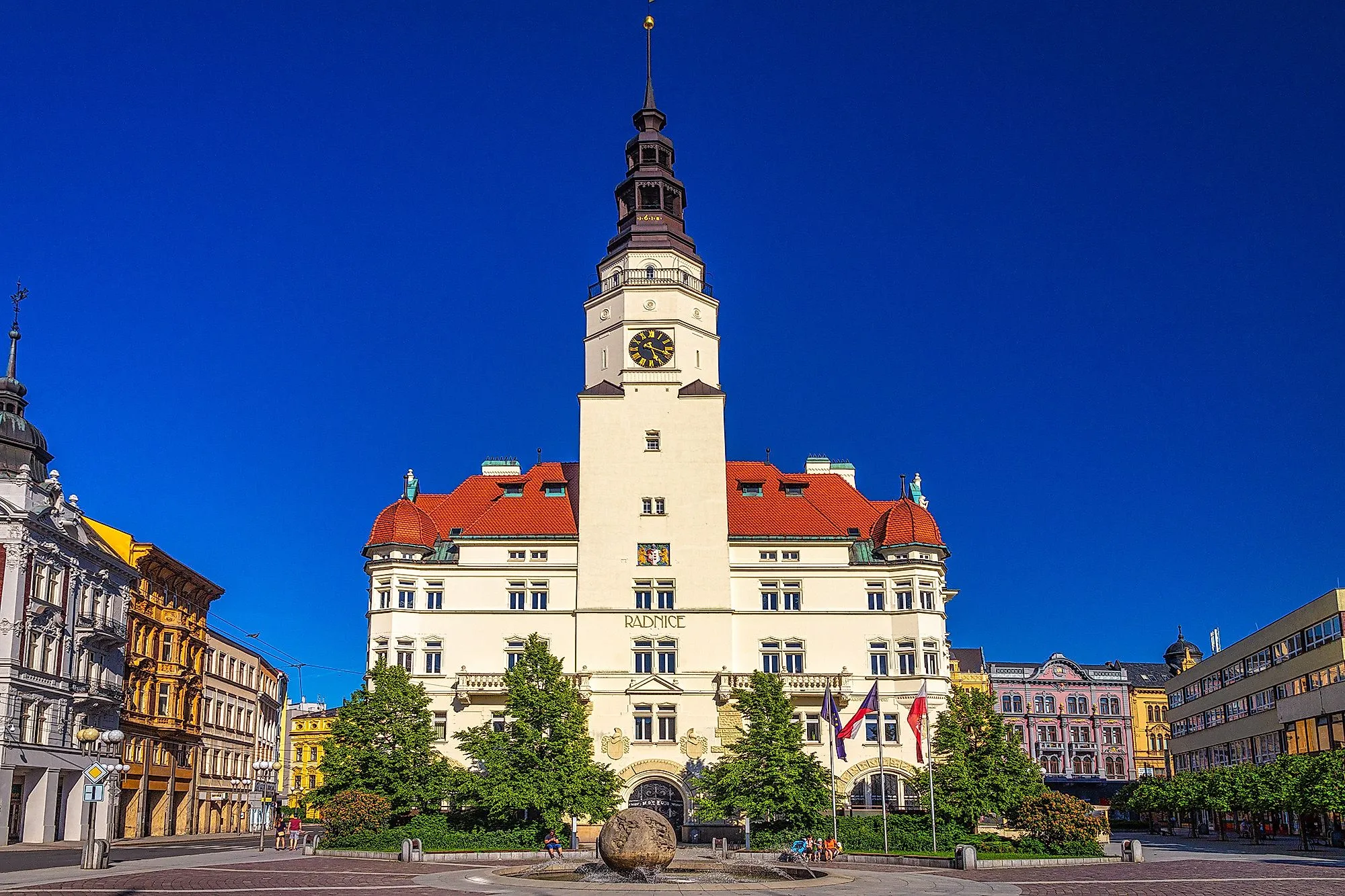 Historická radnica v Opave s vežou a fontánou na námestí v slnečnom svetle.