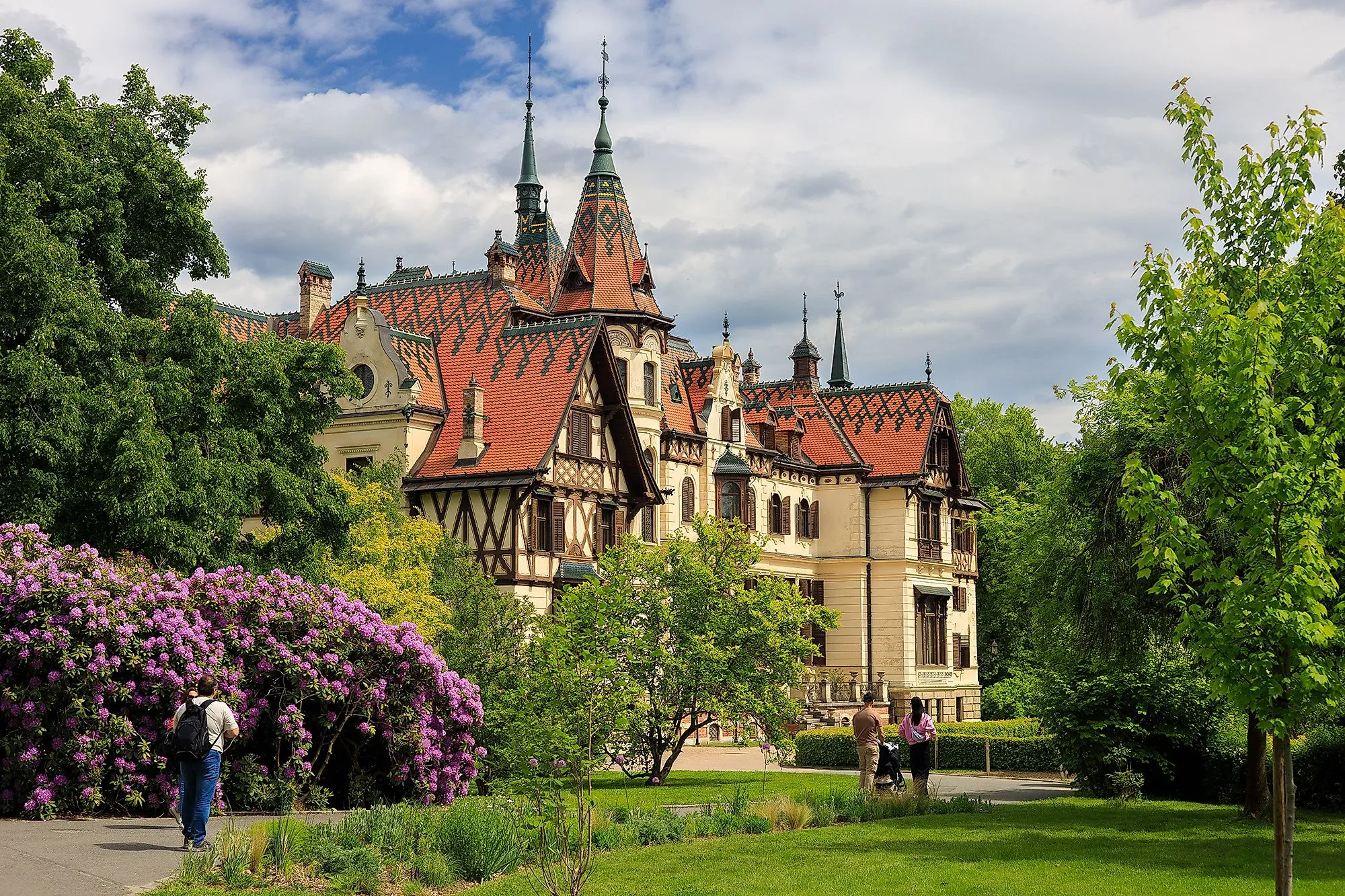 Schloss Lešná in Zlín, umgeben von Park und blühenden Rhododendren im Frühling.