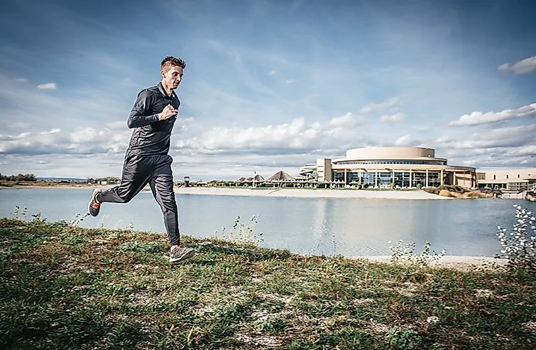 Jogger rent langs de oever van het meer voor de St. Martins Therme & Lodge in Burgenland
