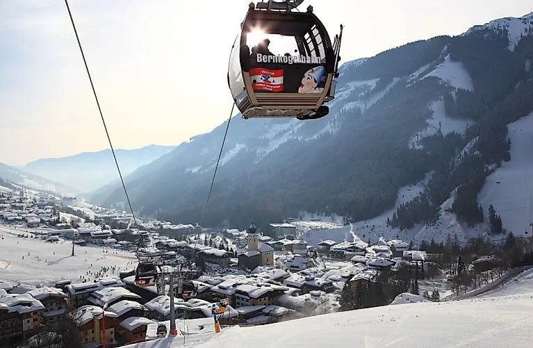 Winter view of Saalbach with snow-covered roofs and the floating Bernkogelbahn in the foreground.