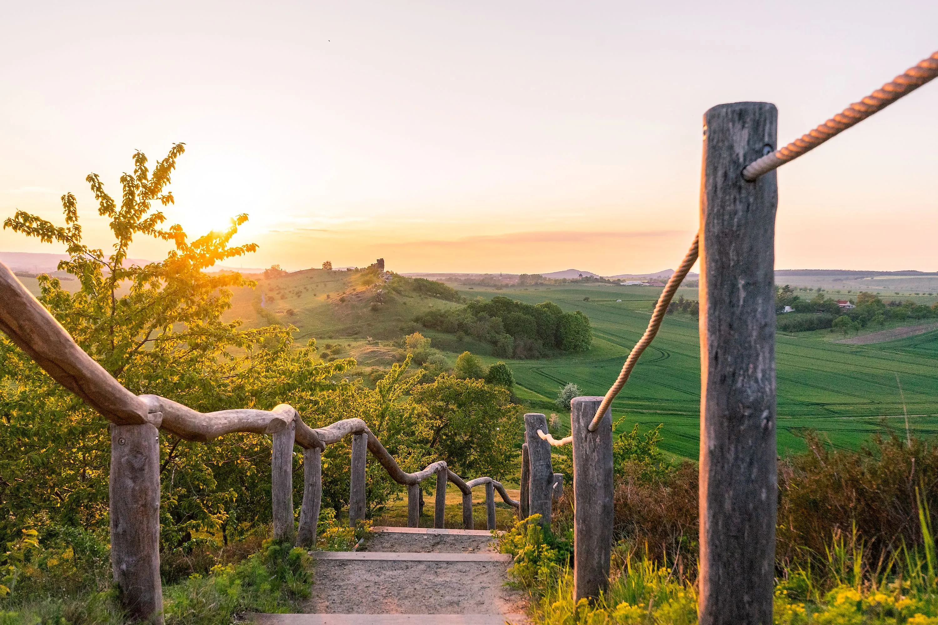 Sentier de randonnée avec balustrade en bois près de Weddersleben avec vue sur les champs verts au coucher du soleil