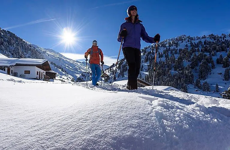 Dos personas caminan con raquetas de nieve en un soleado día de invierno en la región de Silber Karwendel, cerca de Schwaz, rodeadas de montañas nevadas.