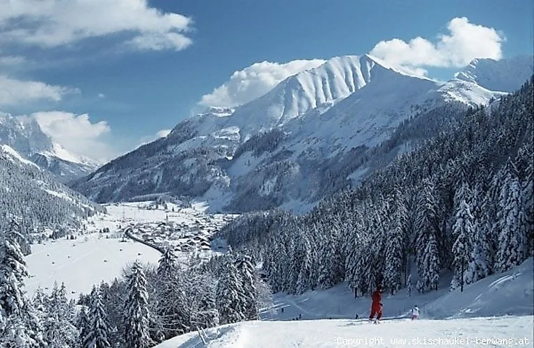 Winterliches Panorama des Skigebiets Berwang mit verschneiten Skipisten, Skifahrern und majestätischen Bergen im Hintergrund.