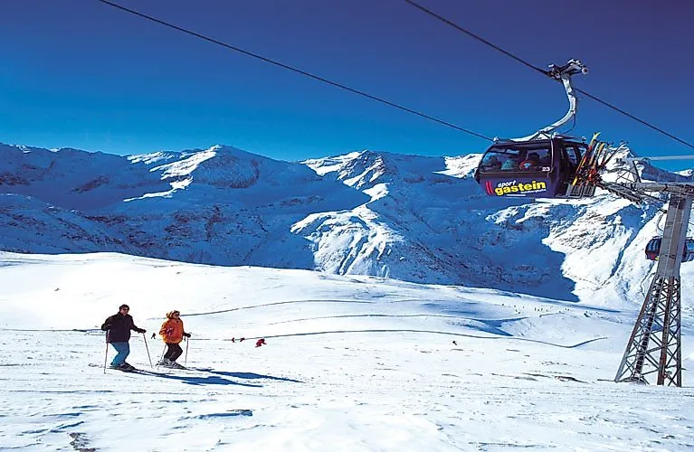 Skiers on the snow-covered slopes in the Gastein Valley with a view of the surrounding Alps.