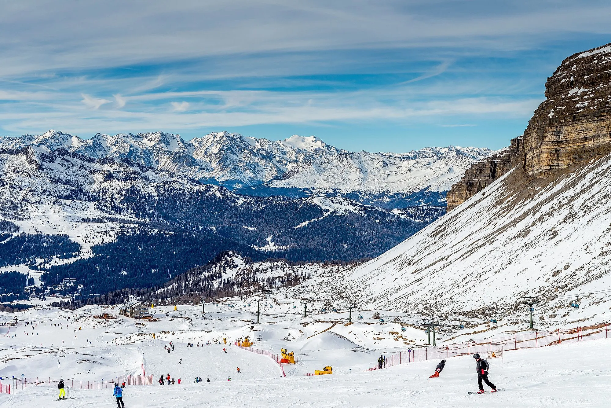 Lyžaři na zasněžených svazích Madonny di Campiglio v Trentinu s výhledem na majestátní Dolomity.