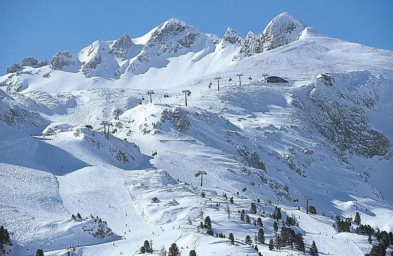 Zasněžené vrcholy a sjezdovky v lyžařské oblasti Obertauern - lanovky, lyžaři a fantastická zimní kulisa uprostřed rakouských Alp.