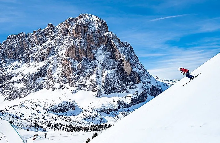 Skiers in St. Christina Val Gardena in front of the impressive Sassolungo massif in the Dolomites.