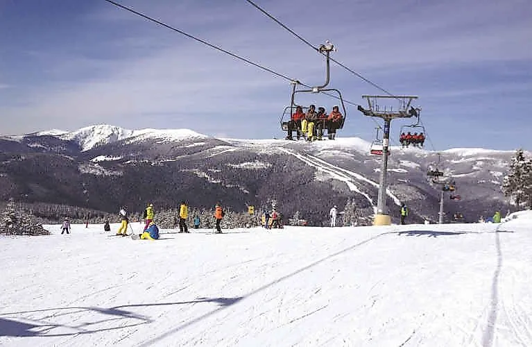 Skifahrer und Sessellift im Wintersportgebiet Spindlermühle mit schneebedeckten Hängen und Panoramablick