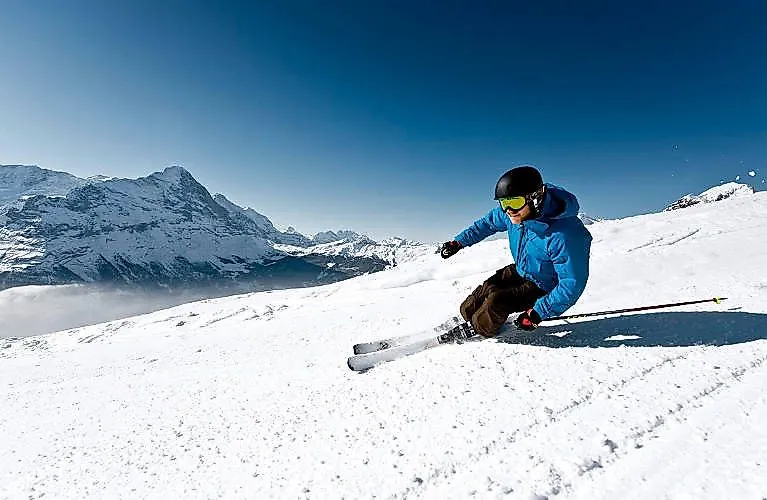 Skifahrer in Aktion auf der Piste mit Blick auf das verschneite Bergpanorama bei Grindelwald.
