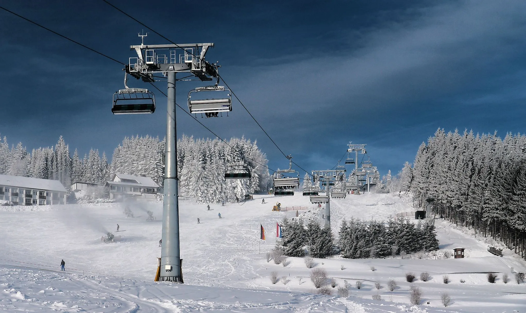 View of the ski slope on the Ritzhagen in Willingen with modern chairlifts and snow-covered fir trees.