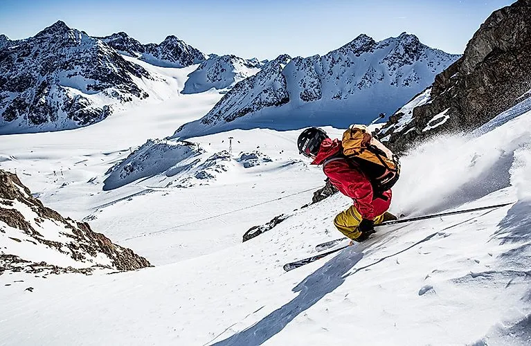 Esquiador con chaqueta roja esquiando fuera de pista en el glaciar nevado de Pitztal, en Tirol.