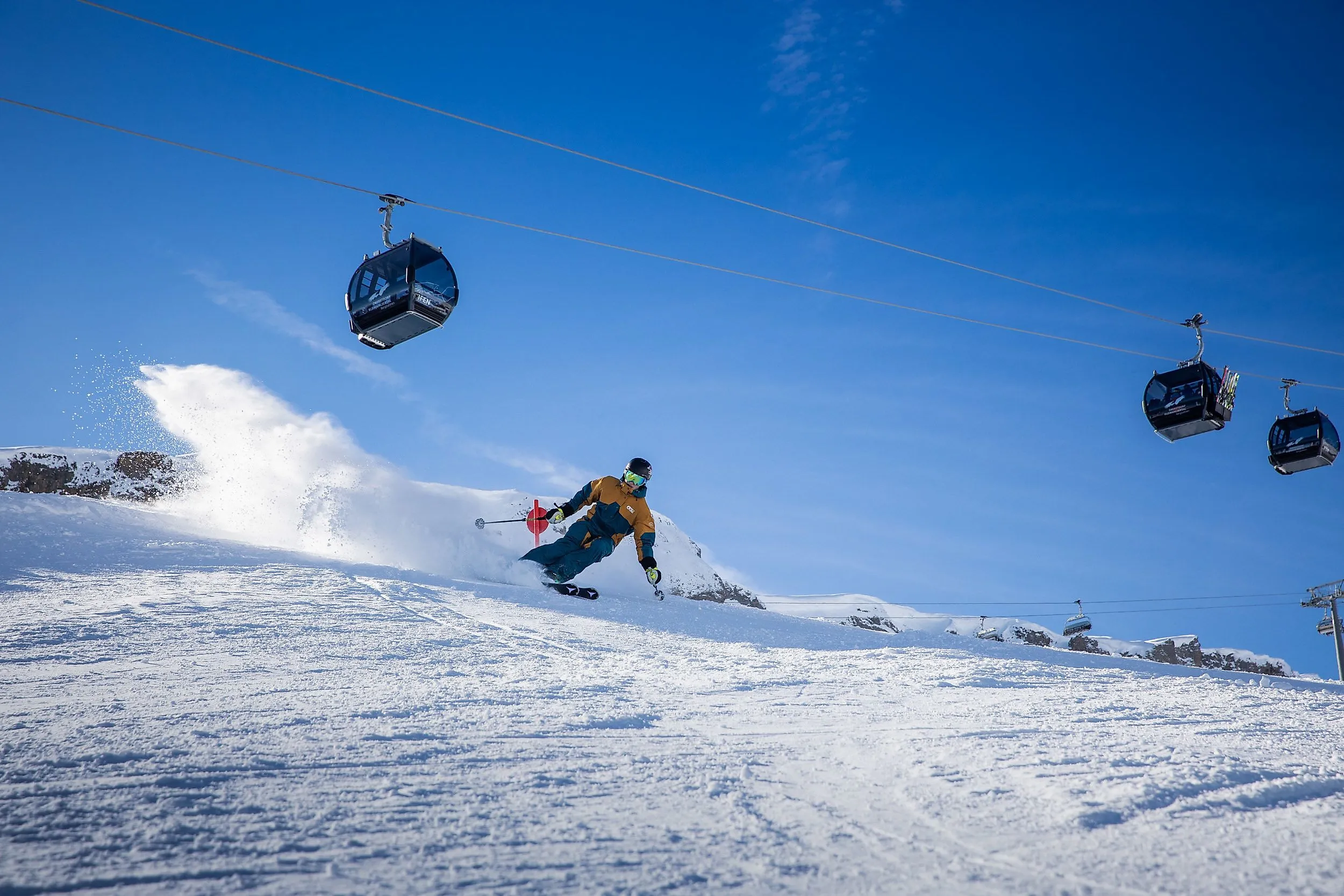 Skiërs skiën bergafwaarts in het Ifen skigebied in Kleinwalsertal onder een moderne gondellift