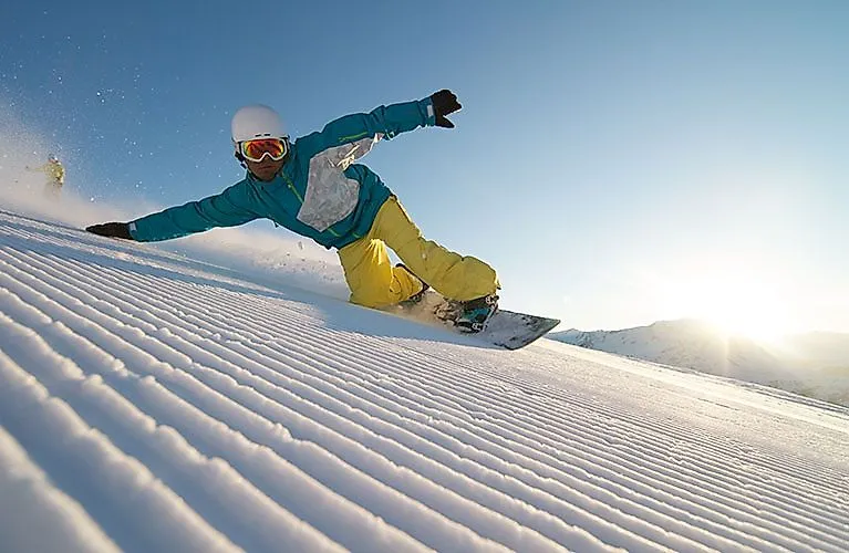 Snowboarder glijdt in de zon over een vers geprepareerde piste in Nauders.