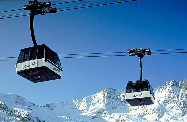 Zwei Gondeln der Seilbahn schweben über verschneiten Bergen im Skigebiet Saas-Fee.