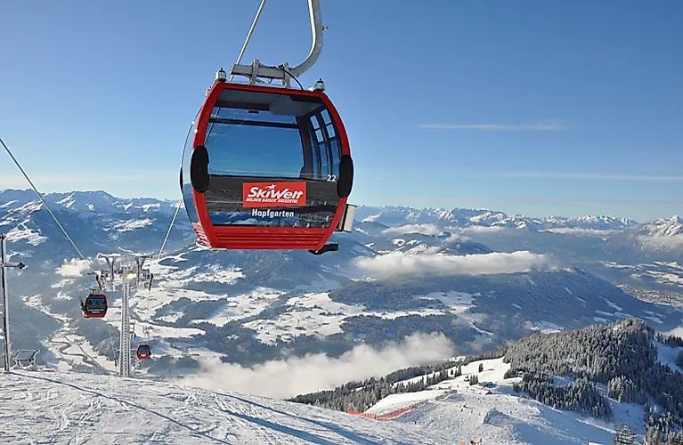 Red gondola of the SkiWelt Wilder Kaiser-Brixental floats over the snowy winter landscape near Scheffau in Tyrol.