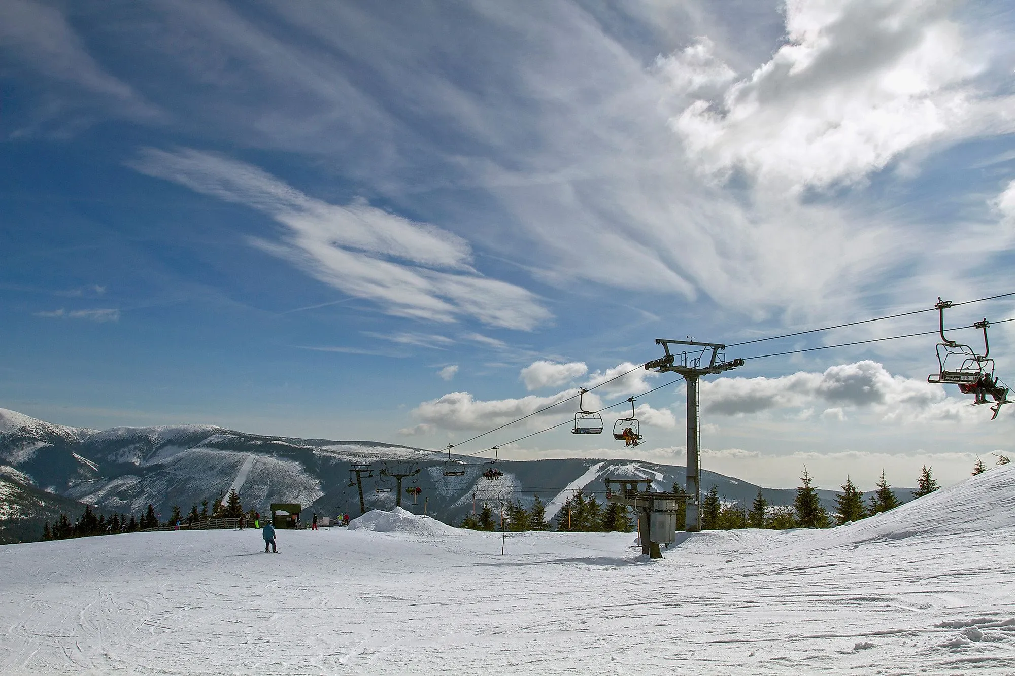 Skiërs en stoeltjeslift in het Špindlerův Mlýn skigebied in het Reuzengebergte in de zon.
