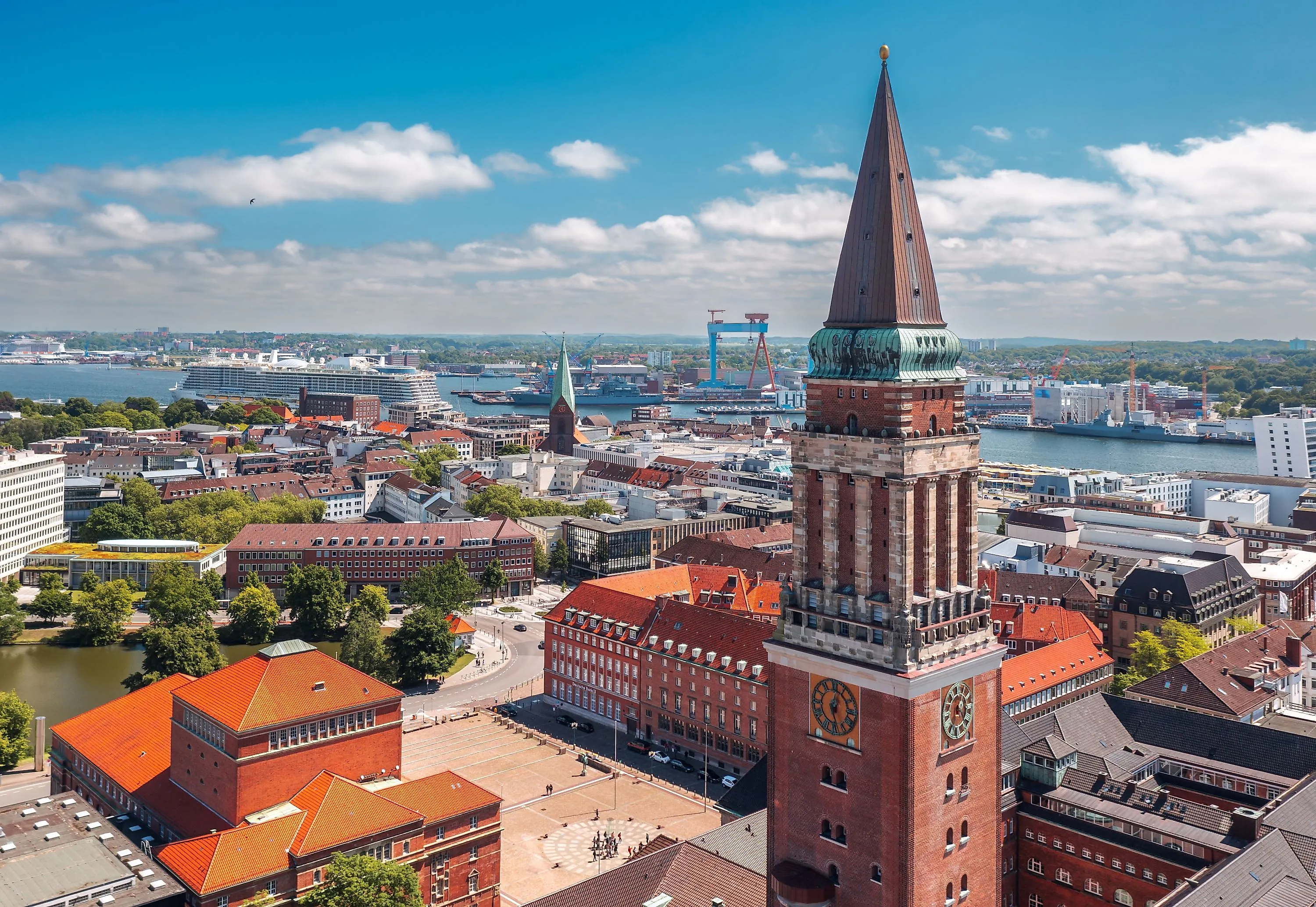 Kiel s radnicí a přístavem, výletními loděmi a loděnicemi v pozadí
