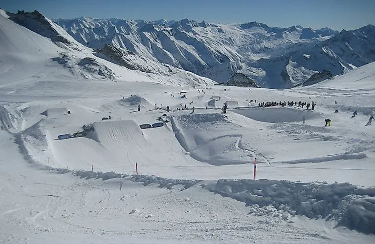 Actionreicher Snowpark auf dem Hintertuxer Gletscher mit Halfpipes, Sprüngen und Skifahrern inmitten der verschneiten Berglandschaft.