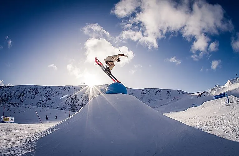 Snowboardista skáče cez prekážku v snowparku Turracher Höhe na slnku
