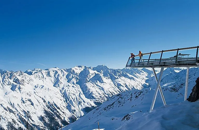 Vue panoramique sur un paysage de montagne enneigé à Sölden avec des visiteurs sur une plate-forme d'observation en hiver.