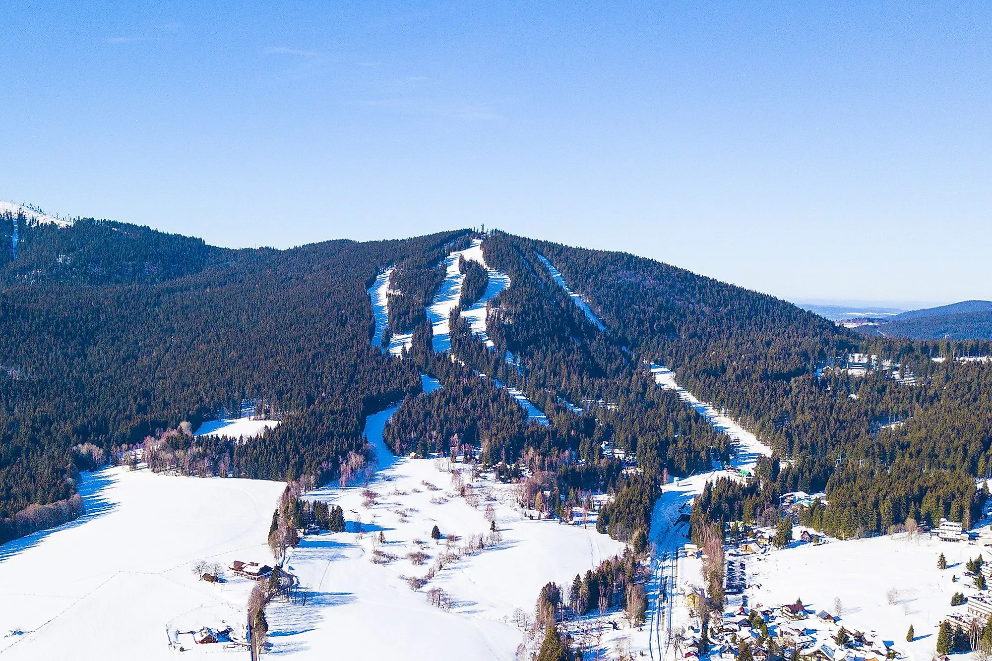 Špičák skigebied bij Železná Ruda met besneeuwde pistes en uitzicht op bossen en bergen.