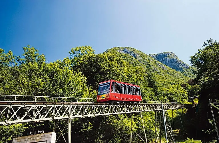 Ozubnicová železnica vedie cez zelené lesy na Monte San Salvatore vo Švajčiarsku