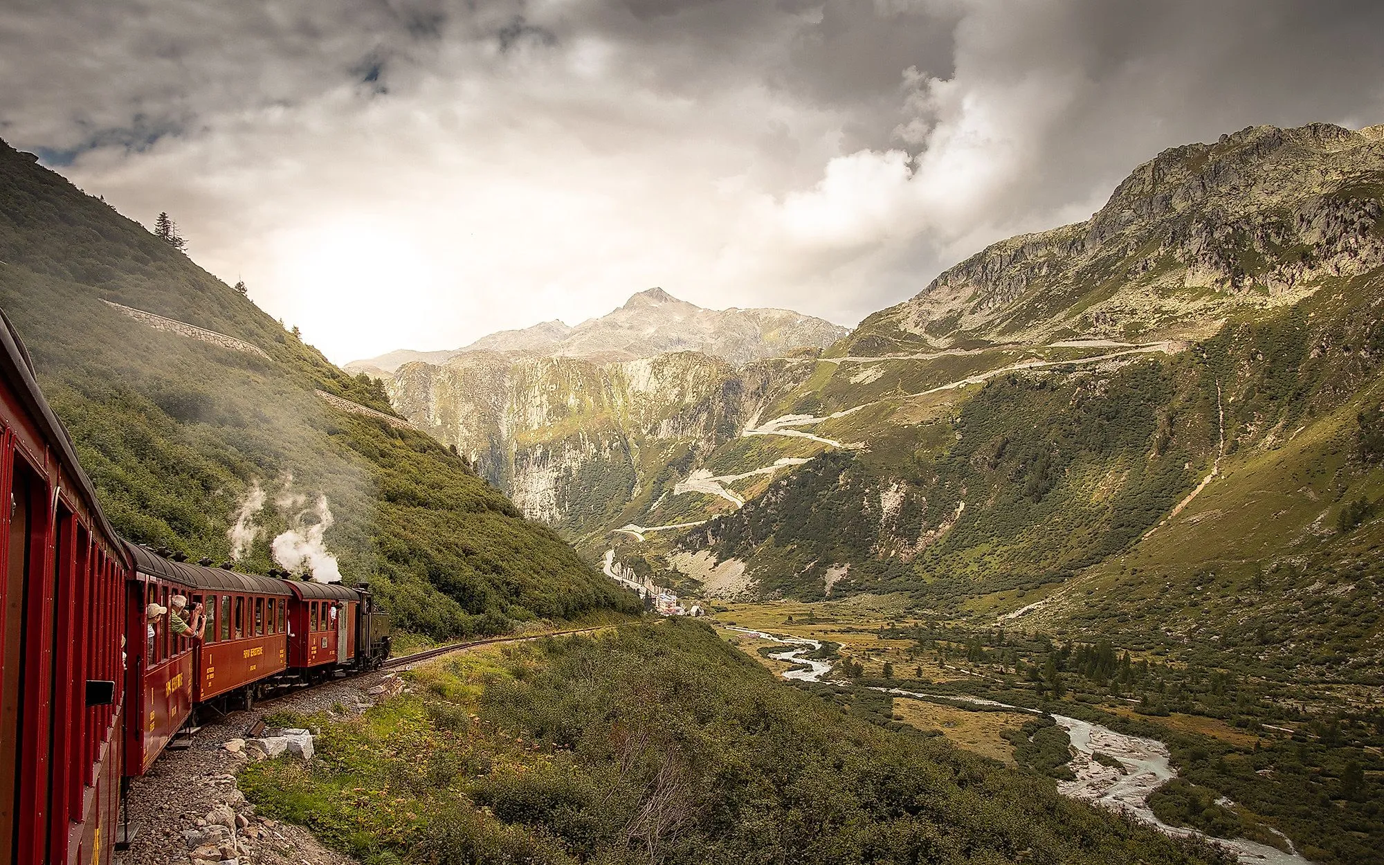 De historische Furka stoomtrein baant zich een weg door het groene Rhônedal in Wallis, omringd door majestueuze bergen.