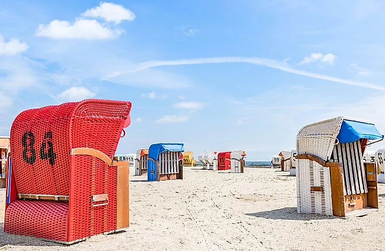 Colorful beach chairs on the sandy beach of Schillig on the North Sea under a blue sky