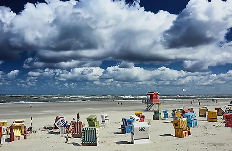 Des chaises de plage colorées sur la plage de sable de Langeoog sous un ciel nuageux spectaculaire