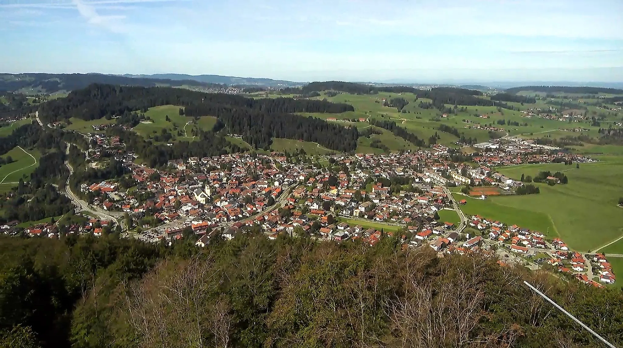 Blick über Oberstaufen im Allgäu mit Ortszentrum, grünen Wiesen und bewaldeten Hügeln