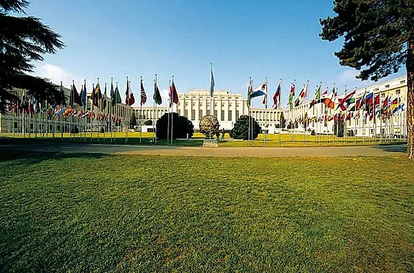 Sídlo OSN v Ženevě s mnoha národními vlajkami před budovou