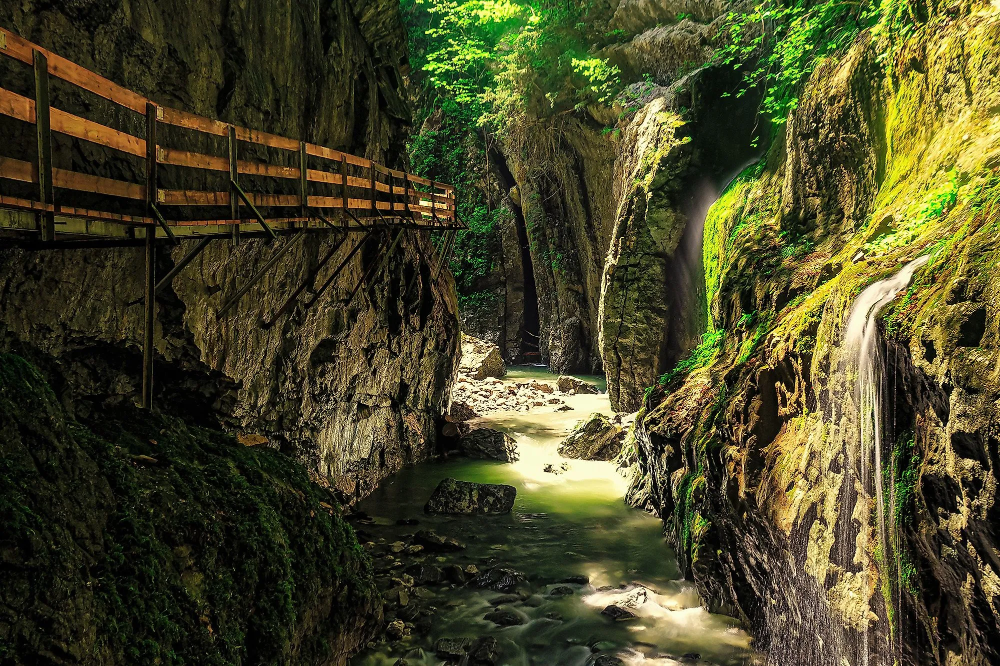 Wooden footbridge through the Alploch gorge near Dornbirn with waterfall and rocks