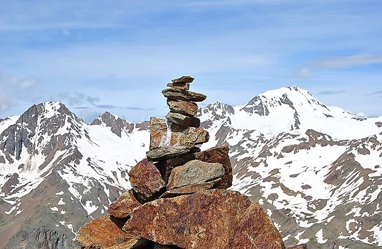 Cairns na pozadí zasněžených vrcholků ve Val Senales.