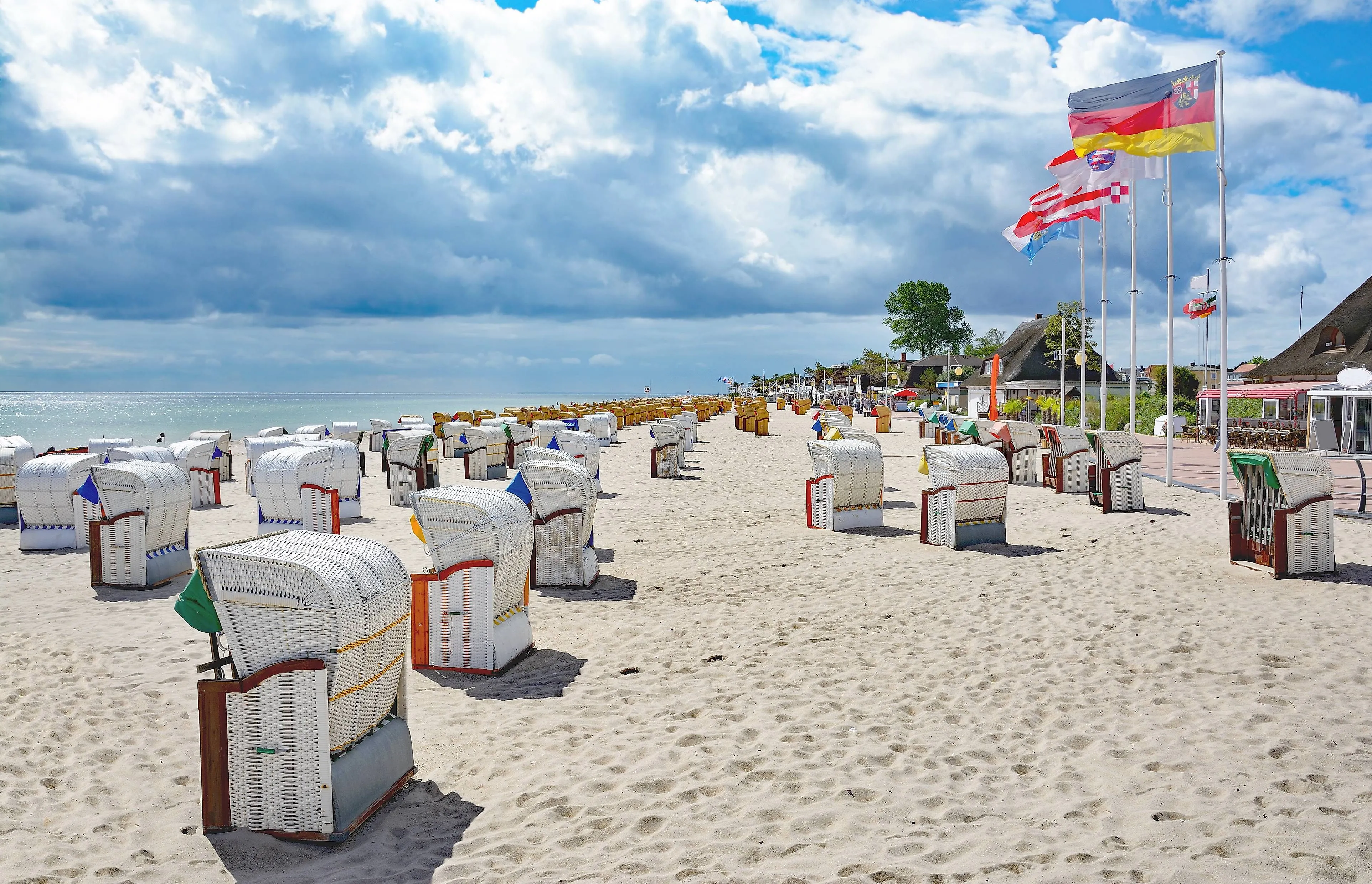 Lehátka na široké písečné pláži v Dahme u Baltského moře s promenádou a vlajkami