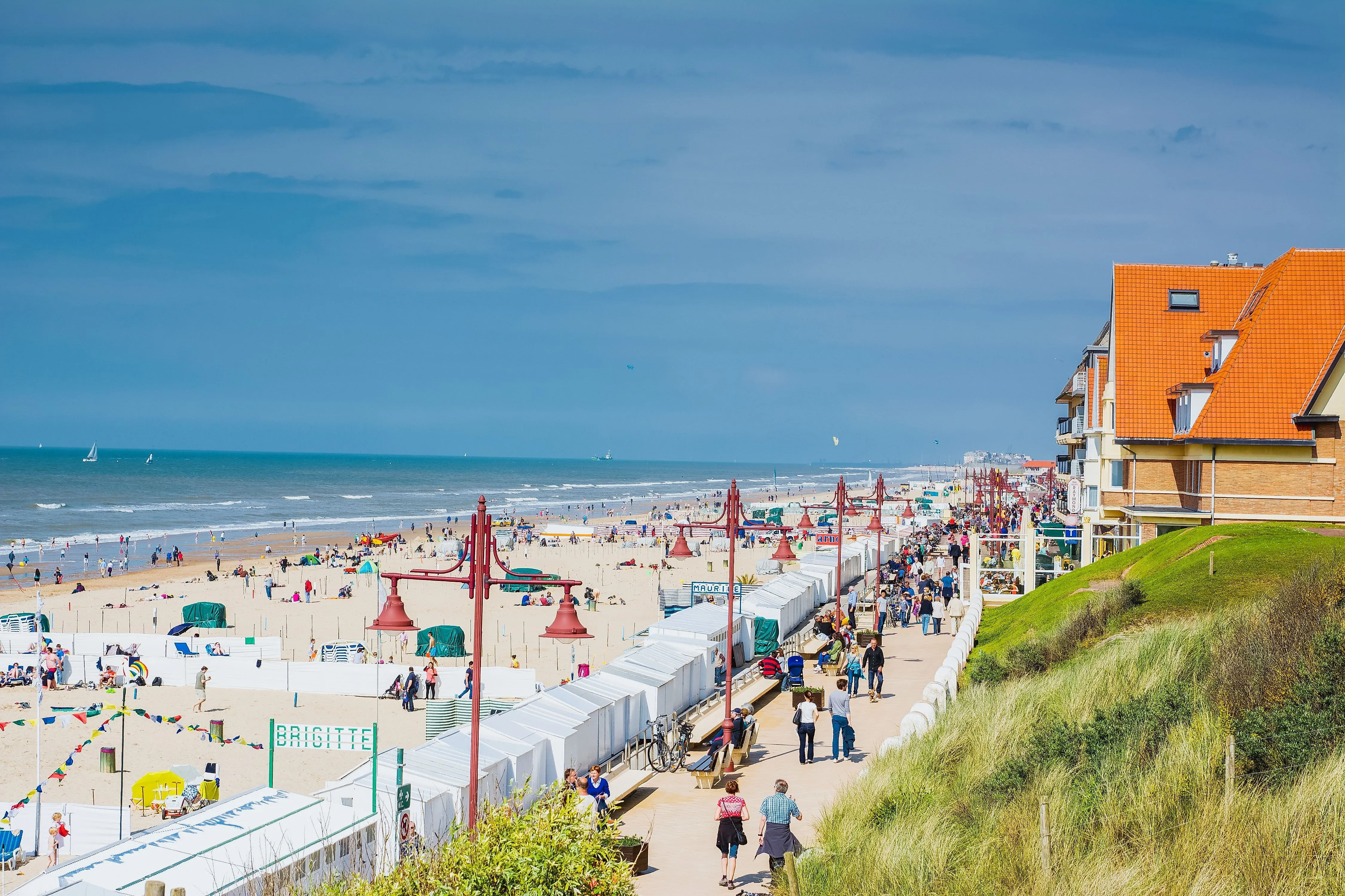 Beach promenade of De Haan on the Belgian coast with many visitors and beach tents