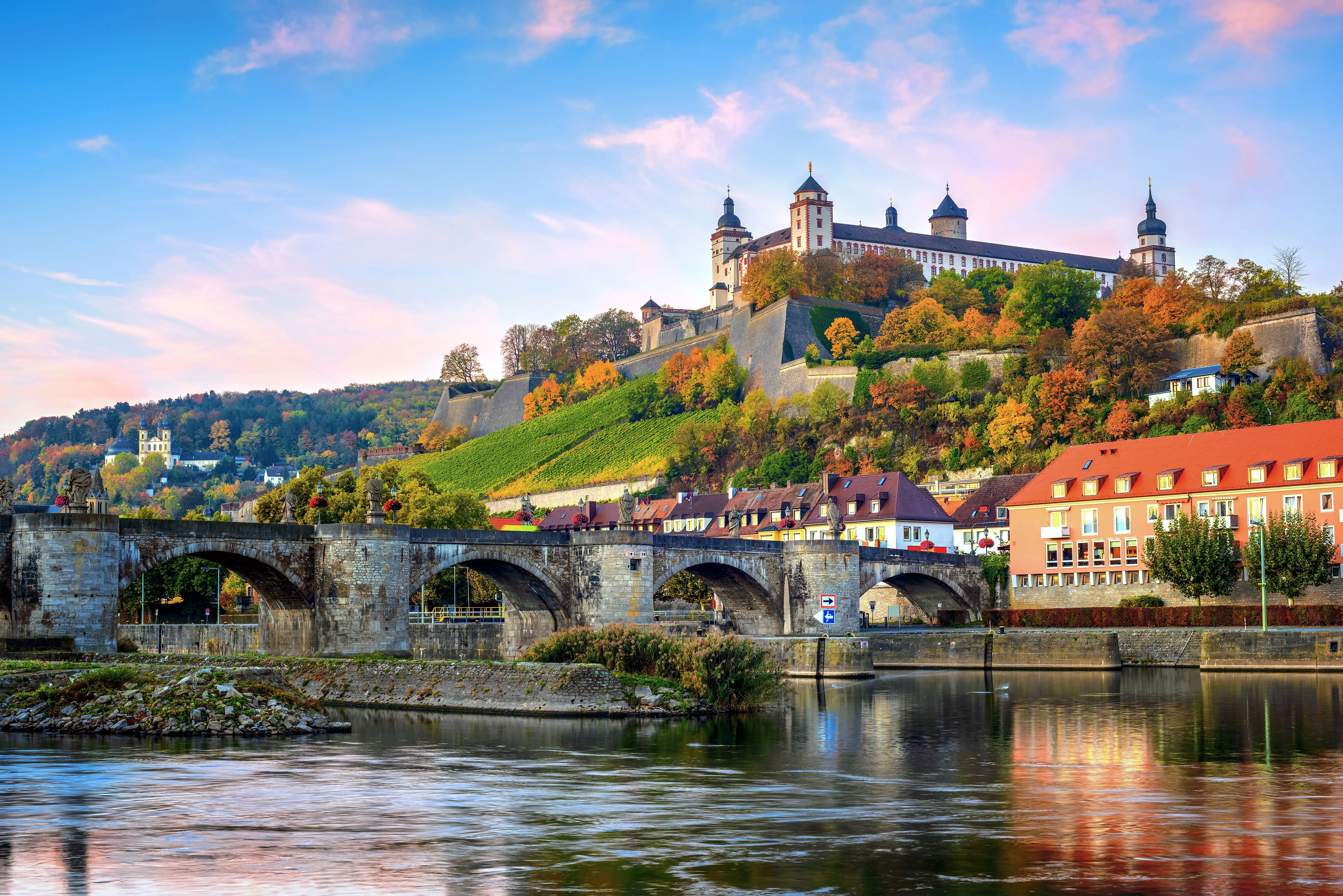 Pevnost Marienberg se tyčí nad Mohanem a starým hlavním mostem ve Würzburgu v podzimním večerním světle.