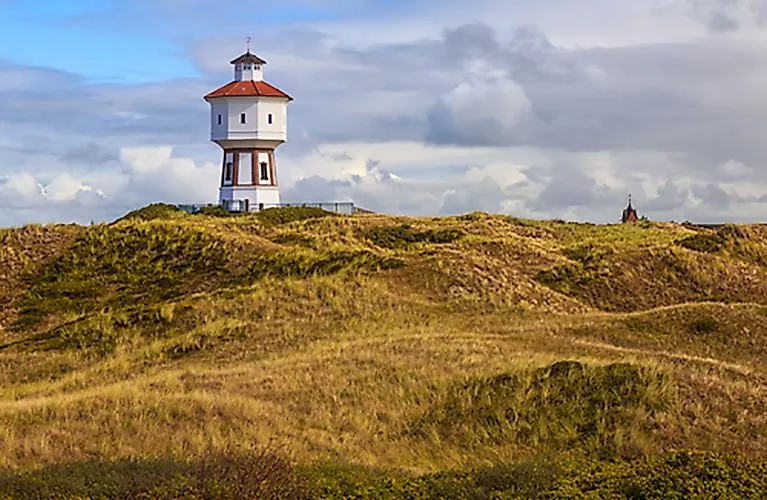 Leuchtturm auf Langeoog inmitten der Dünenlandschaft mit dramatischem Himmel