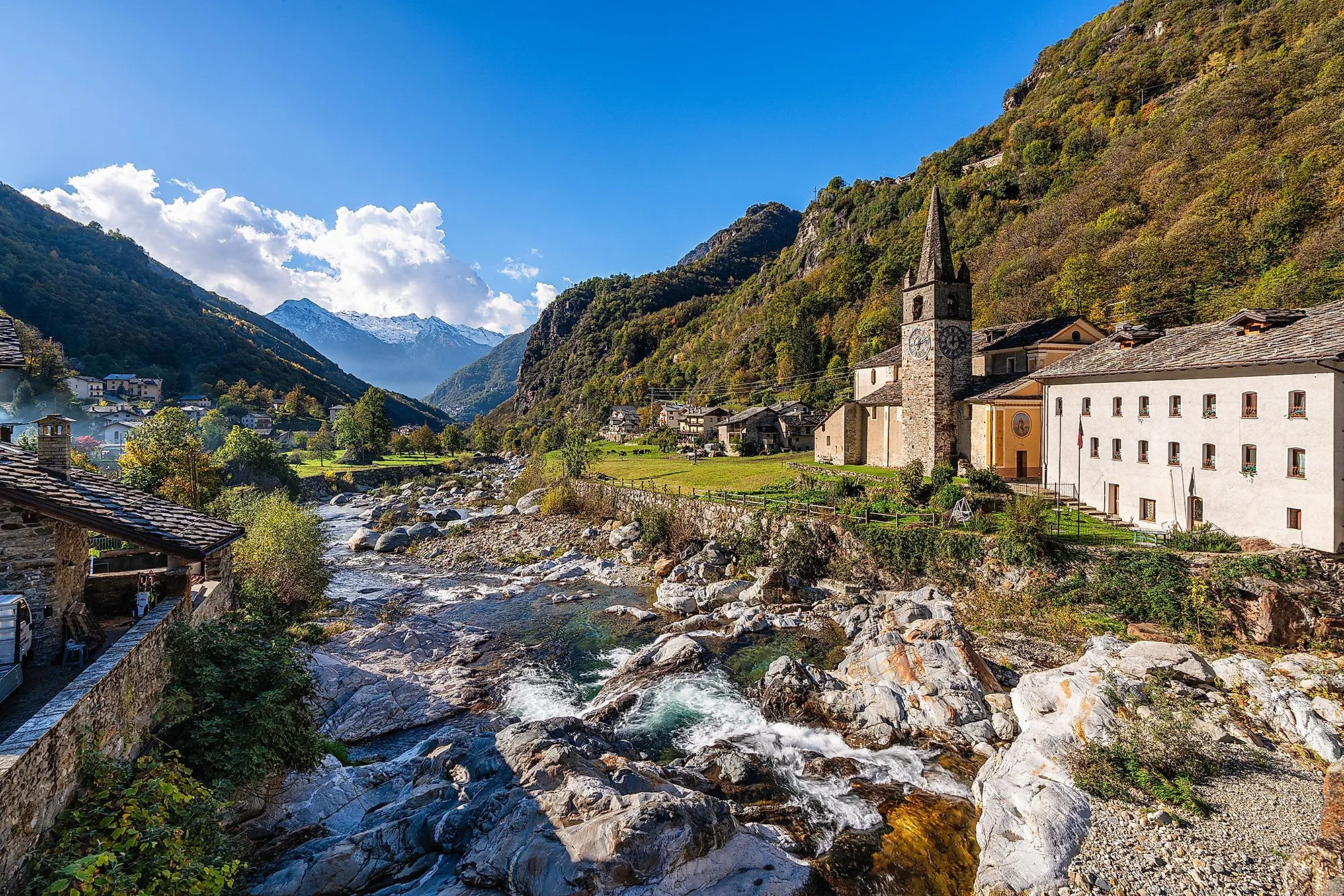 Horská vesnice s kostelem v údolí Lys, zelené dno údolí a zasněžené hory