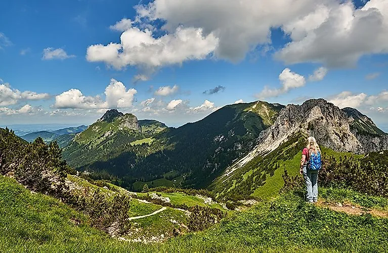 Wandelaar met rugzak kijkt naar het indrukwekkende Alpenpanorama in Grän in het Tannheimer Tal op een zonnige dag.