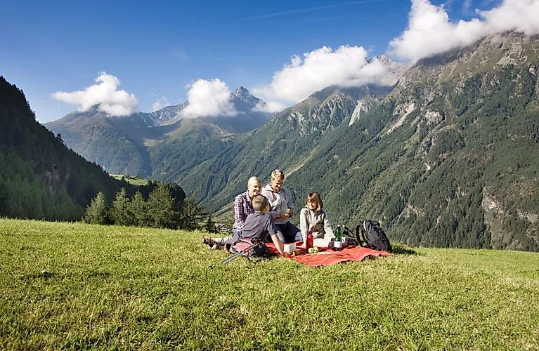 Rodina na pikniku na zelené louce v horách u Oetzu v Ötztalu za slunečného turistického dne.