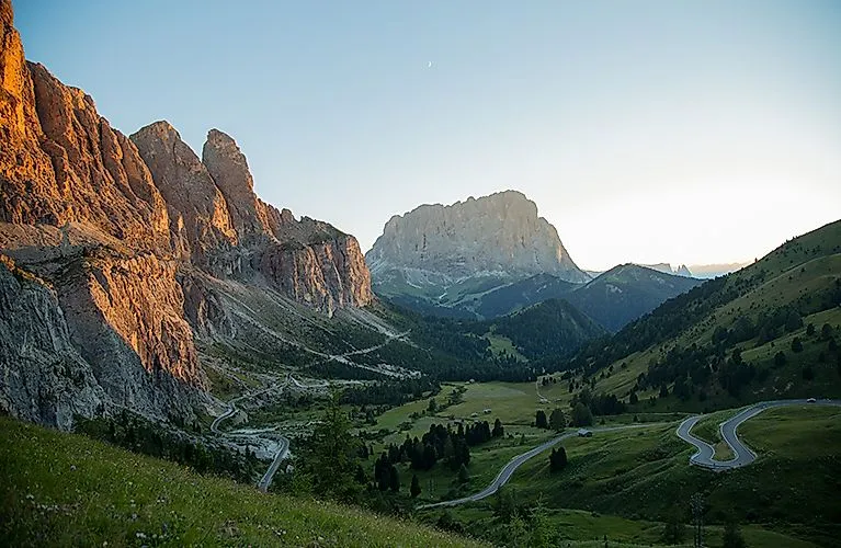 Sunset over the Dolomites near St. Christina with serpentines and a green valley.