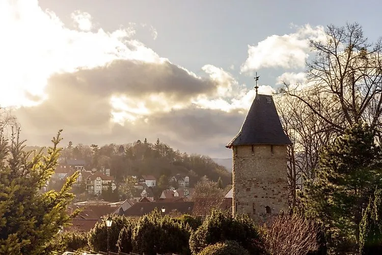 View of Wernigerode with historic tower and houses with dramatic sunbeams shining through the clouds.