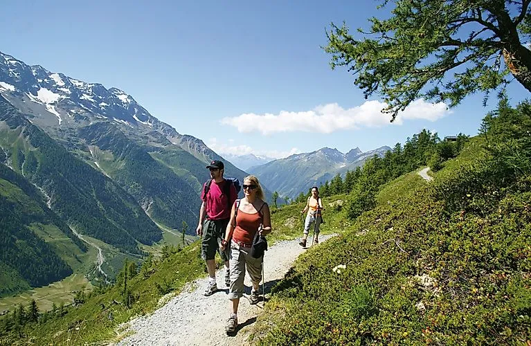 Hikers on a mountain path near Wiler in the Lötschental with a view of the valley and the Alps
