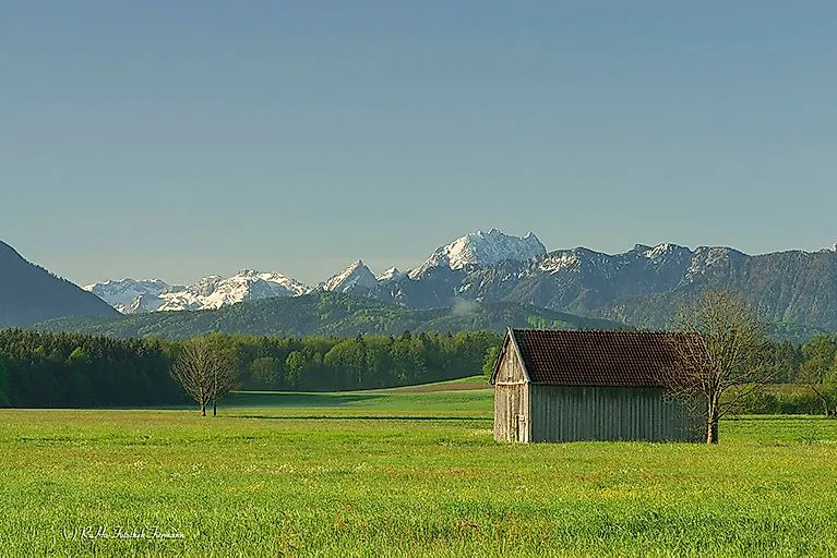 Summery Alpine panorama near Anger with green meadow, hut and mountain range