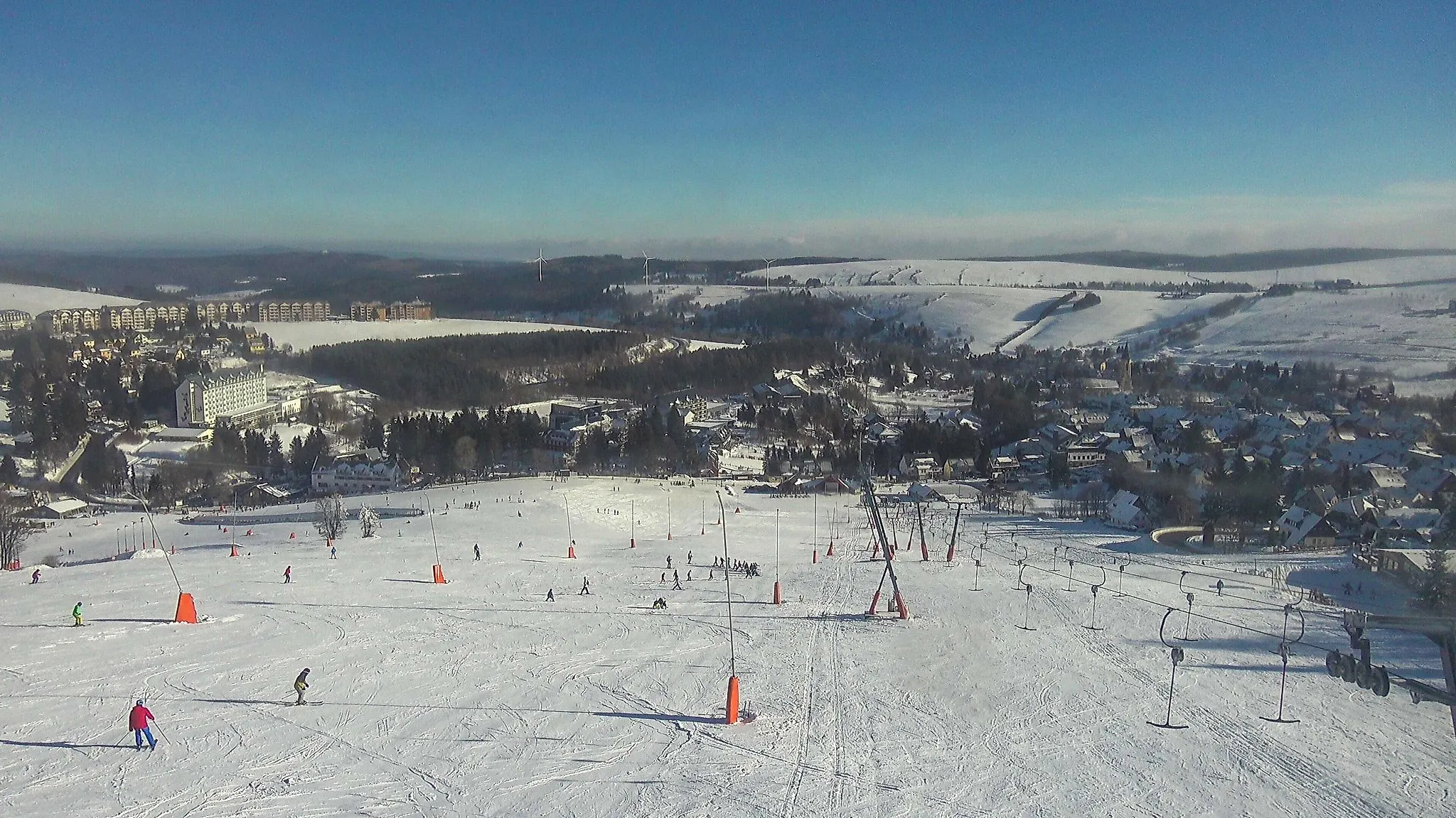 Skifahrer am Fichtelberg in Oberwiesenthal auf verschneitem Skihang bei Sonnenschein