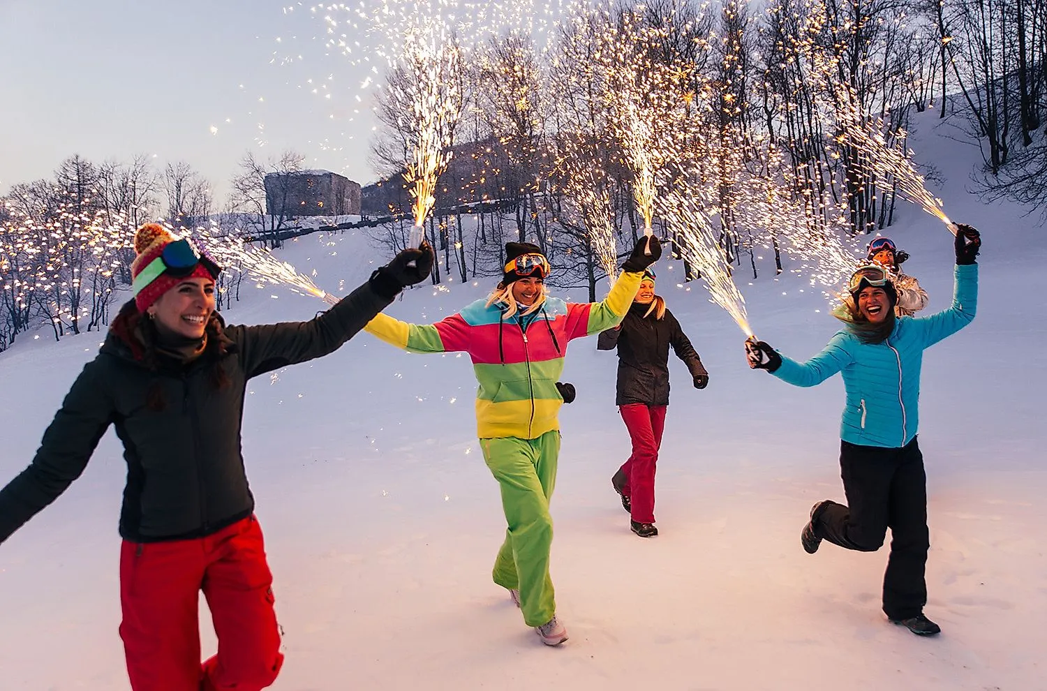 Freundinnen feiern im Schnee mit Wunderkerzen – Wintererlebnis in den Bergen voller Spaß und Stimmung.