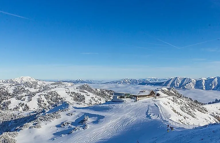 Winterpanorama in Lackenhof am Ötscher mit verschneiter Berglandschaft, Skipisten und Bergrestaurant bei klarem Himmel.