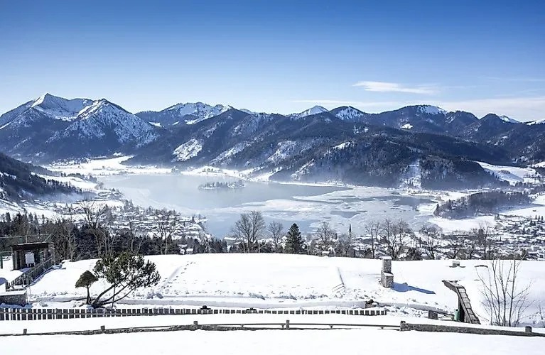 Winterliche Aussicht auf das verschneite Schliersee mit Bergen und teilweise zugefrorenem See